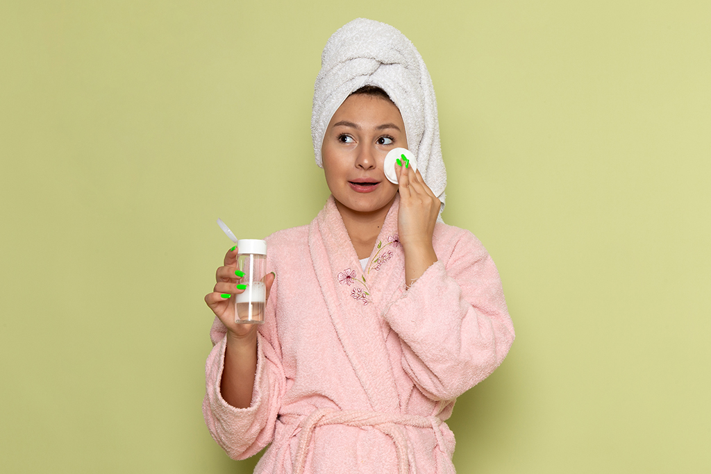 female pink bathrobe cleaning up all make up from her faceedit